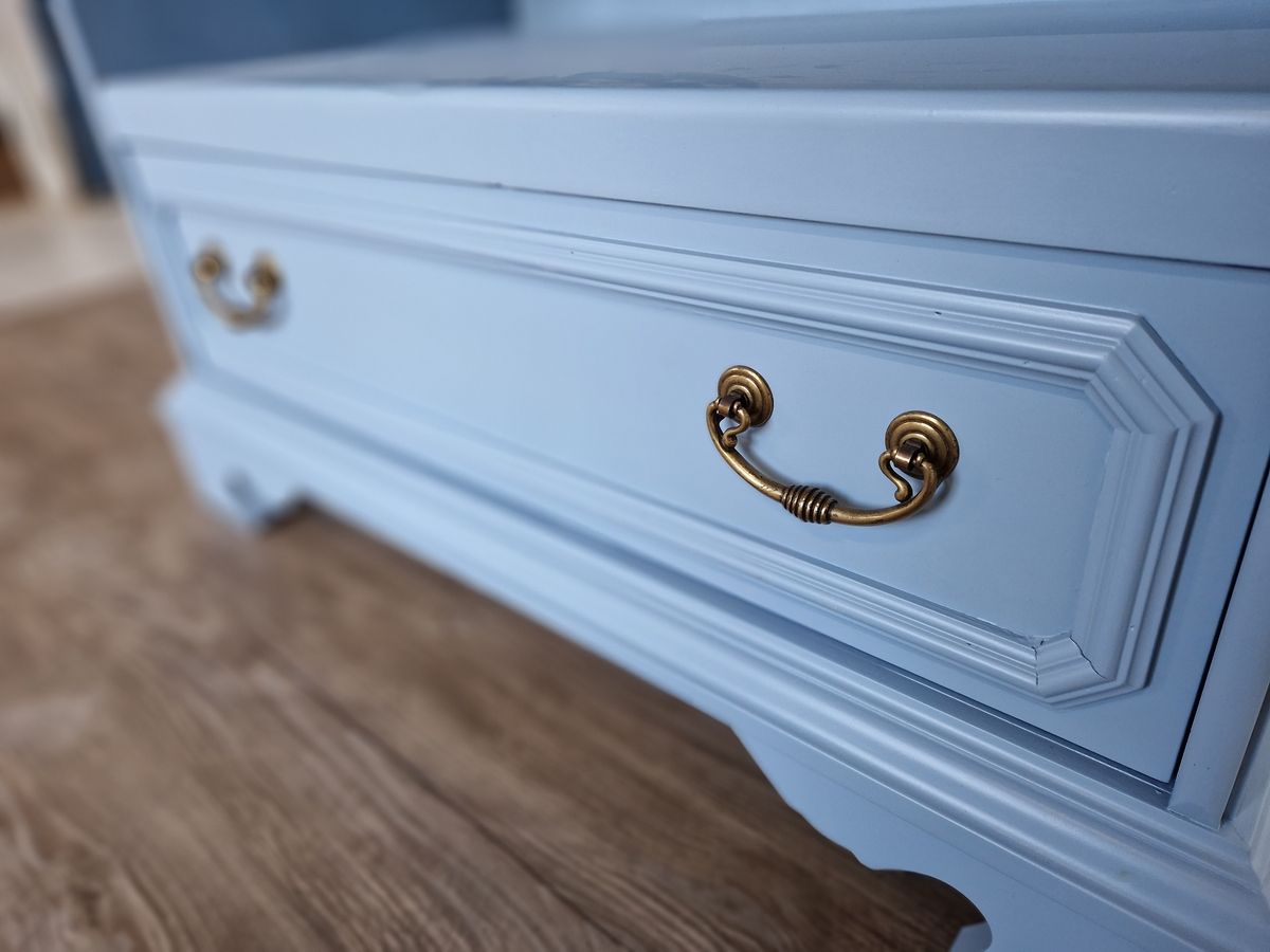 Restaurierte Kommode in Blau - Nahaufnahme einer klassischen, hellblauen Kommode mit goldfarbenen Griffen und filigranen Verzierungen.